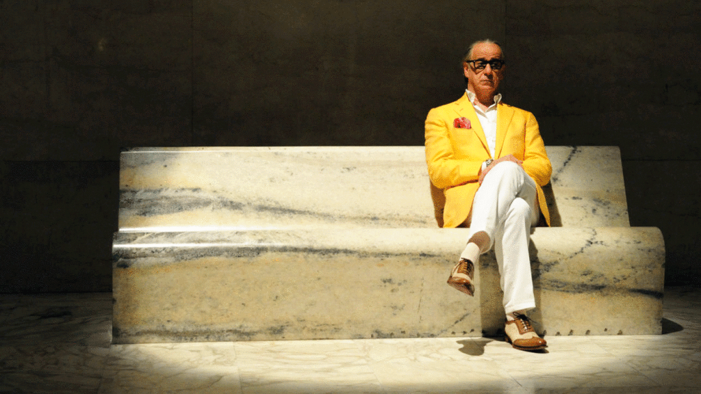 Toni Servillo sitting in yellow suit and pondering. Film - The Great Beauty