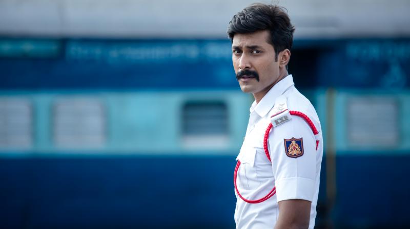 Rishi wearing Traffic cop dress in front of a train in Kavaludaari film, dir. Hemanth Rao