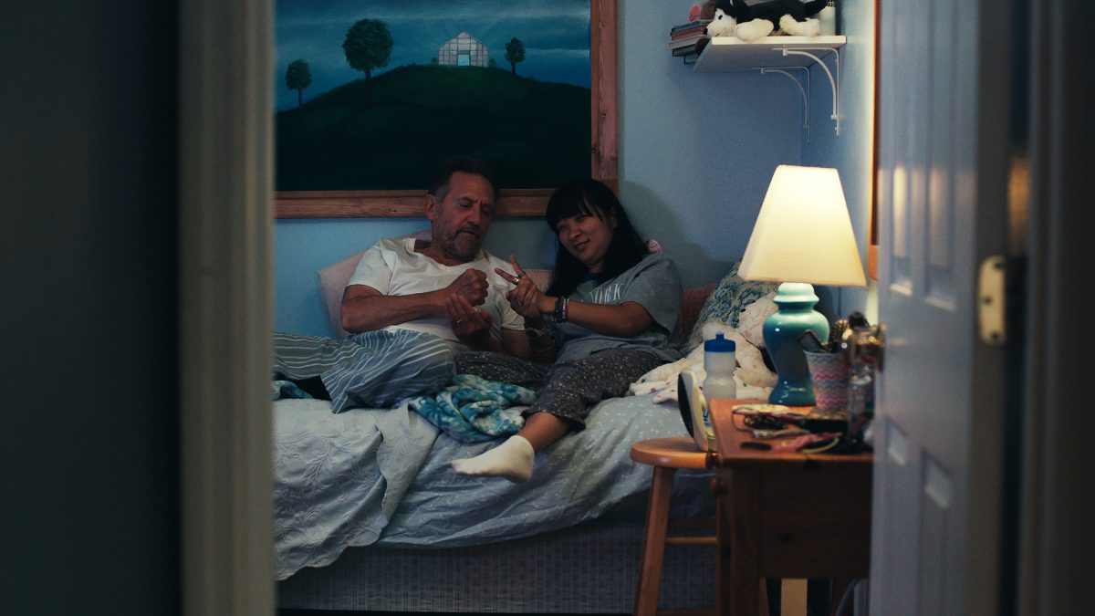 The thing that stays with you the most in Liz Sargent's debut feature, 'Take Me Home,' is the amount of personality she brings to her protagonist, Anna, without letting her be defined by her disability. Anna is brazen, self-assured, and assertive in a way that is rarely seen in cinema. There have, unfortunately, been only a few cases where the story offered disabled persons agency and control over their fate without being reductive. I still remember a film from a few years ago that used the character's condition merely as a plot device to build a cloying melodrama, while focusing on the parents' pain and plight, leaving the character to appear as a crutch — a harmful trope that exploits sympathy by placing helplessness at the narrative core.There have been many cases where ill-informed, ableist notions disregarded the very purpose of telling such stories. Instead of genuinely caring about what they are trying to say with the script, the makers seemed almost entirely preoccupied with presenting themselves in a certain light, simply for telling such a story. None of that remotely applies to Sargent's feature film, or even her eponymous 2023 short, of which her feature offers a bracing narrative extension to. The short film followed Anna, a 30-something Korean-American woman, on a particularly stressful day in her life. Sargent used that premise to address the damning gaps in the American healthcare system, while also telling a gentle tale of sisterhood.   Even when a few narrative beats revealed Anna's sister's frustration in finding Anna a new, comfortable home, that anger was directed at the systemic factors that make this needlessly challenging and tiresome, but never at Anna. The final moments also tied the story in a way that replaced the usual narrative trap of recovery by focusing on the power of emotional embrace. The same applies to Sargent's debut feature, which follows Anna's journey toward reclaiming her agency, where the obstacle is a systemic one, not any flaw in her state of being. In that context, it is also a feminist tale because the character doesn't get what she wants / needs by changing herself, nor does the script present some aspects of her character as something she needs to alter or overcome.  The feature film extends the scope of the earlier script by exploring Anna's close-knit relationship with her aging parents, Bob (Victor Slezak) and Joan (Marceline Hugot), living in a suburban neighbourhood in Florida. It features mundane moments in the family's life together to offer a sense of its unhurried pace. We see them caring for one another while living through an extreme heat wave, trying to meet each other's demands or needs, while understanding the root of their frustration or grievances. Despite an occasional friction, it doesn't pit them against each other, nor does it show them holding each other back.  We meet a family that is used to each other's behaviors and habits, and trying to find a common ground, just as any other family. That's why the characters feel refreshingly real with distinct personalities. The scenes are written in a way that gives us all these insights organically, without being deliberate or blunt. It's through everyday moments that we learn what independence means for Bob, while being plagued by looming concerns of memory loss. It also offers us a window into Anna's romantic inclinations with grace and respect.  Sargent also fleshes out some in-between moments when characters are merely looking at each other or processing something they have realized. It helps us get a more rounded understanding of their prickly but endearing bond. Sargent's actual sister, who stars in the central role of the same name, holds the film on her shoulders. Her assured turn offers every aforementioned insight about her personality. Ali Ahn, who plays Anna's sister, Emily, is an absolute joy to watch on screen. She presents Emily as an effortlessly breezy presence while straddling a path between her professional and familial responsibilities, ensuring everyone's satisfaction.  Slezak is remarkable in finding the perfect balance in presenting Bob's outward crankiness with a gentle warmth that shows up in those occasional moments when we see him as his vulnerable self. While Sargeant carefully handles this sensitive subject matter, she deserves just as much praise for her filmmaking approach, which focuses on building a few, relatively long scenes without rushing toward any overarching observation. It gives us a richer understanding of their relationship with a lived-in feel, while gradually redefining our notions about adoption, disabilities, and aging. My only gripe about the film would be the way Sargeant connects the second and third acts. The bridge between those defining moments feels rather underdeveloped. It doesn't communicate anything emotionally memorable, nor does it offer a clear narrative thread as it transitions into the film's final beats. Although you understand the logical reasoning behind what happens before and what comes after, the bridge remains the only underwhelming part of the film. Nevertheless, it doesn't take away much from the sensible beauty that the film gleefully radiates with.  Liz Sargent's 'Take Me Home' is a part of the 2026 Sundance Film Festival.  Take Me Home (2026) Movie Links: IMDb, Letterboxd Take Me Home (2026) Movie Cast: Anna Sargent, Ali Ahn, Victor Slezak, Marceline Hugot, Shane Harper, April Matthis, Shannon DeVido, Steve Way