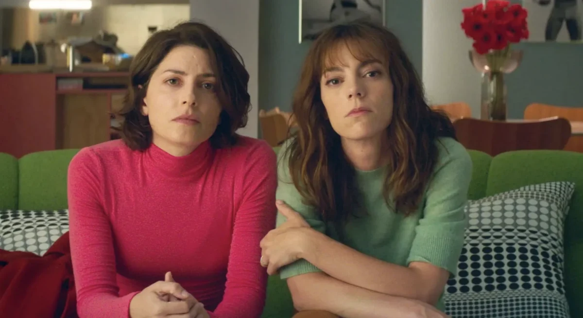 This image shows actresses Bárbara Lennie (left, in the pink turtleneck) and Victoria Luengo (right, in the green top) in the film Bitter Christmas (Amarga Navidad), directed by Spanish filmmaker Pedro Almodóvar